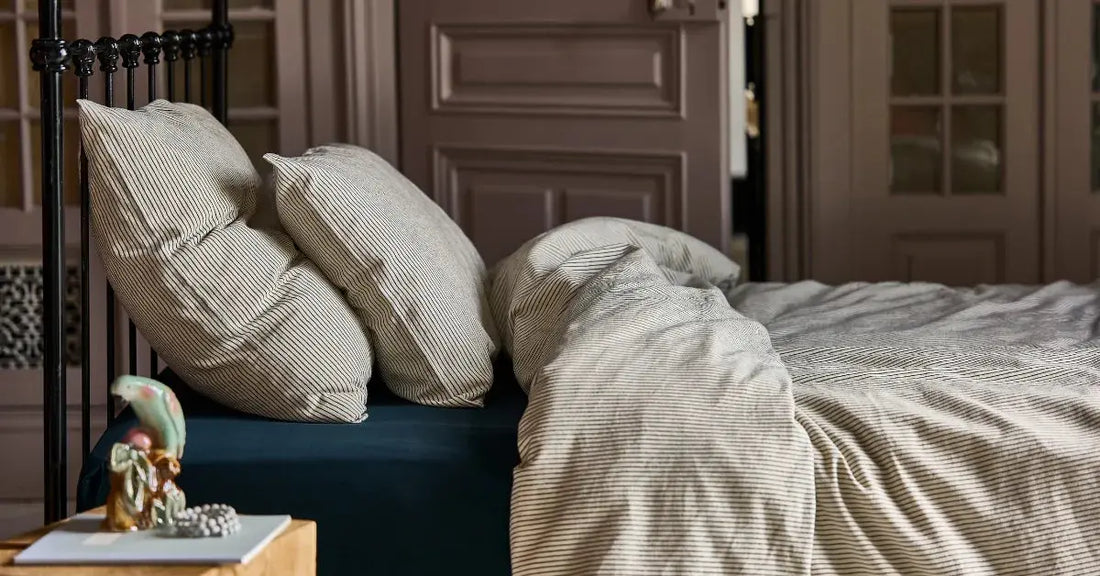 Housse de couette et taies d'oreiller rayé noir sur fond blanc en coton bio, sur un lit