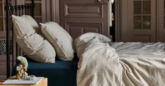 Housse de couette et taies d'oreiller rayé noir sur fond blanc en coton bio, sur un lit