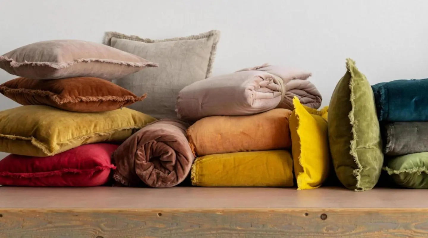 Coussins en promotion posés empilés sur une table plusieurs coloris
