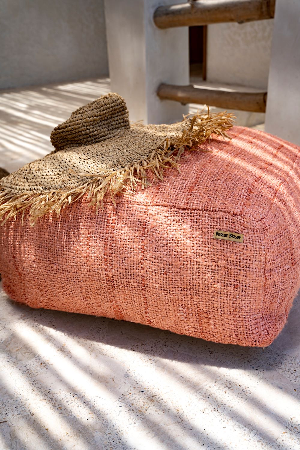 Pouf rose saumon chapeau raphia naturel posé dessus