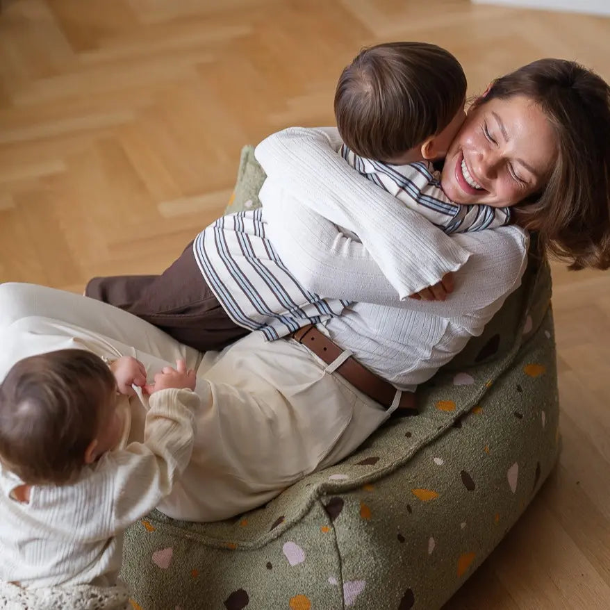 Maman et enfants partageant un moment de tendresse sur un pouf molletonné
