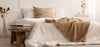 Jeté de lit disposé sur un lit ton beige et blanc
