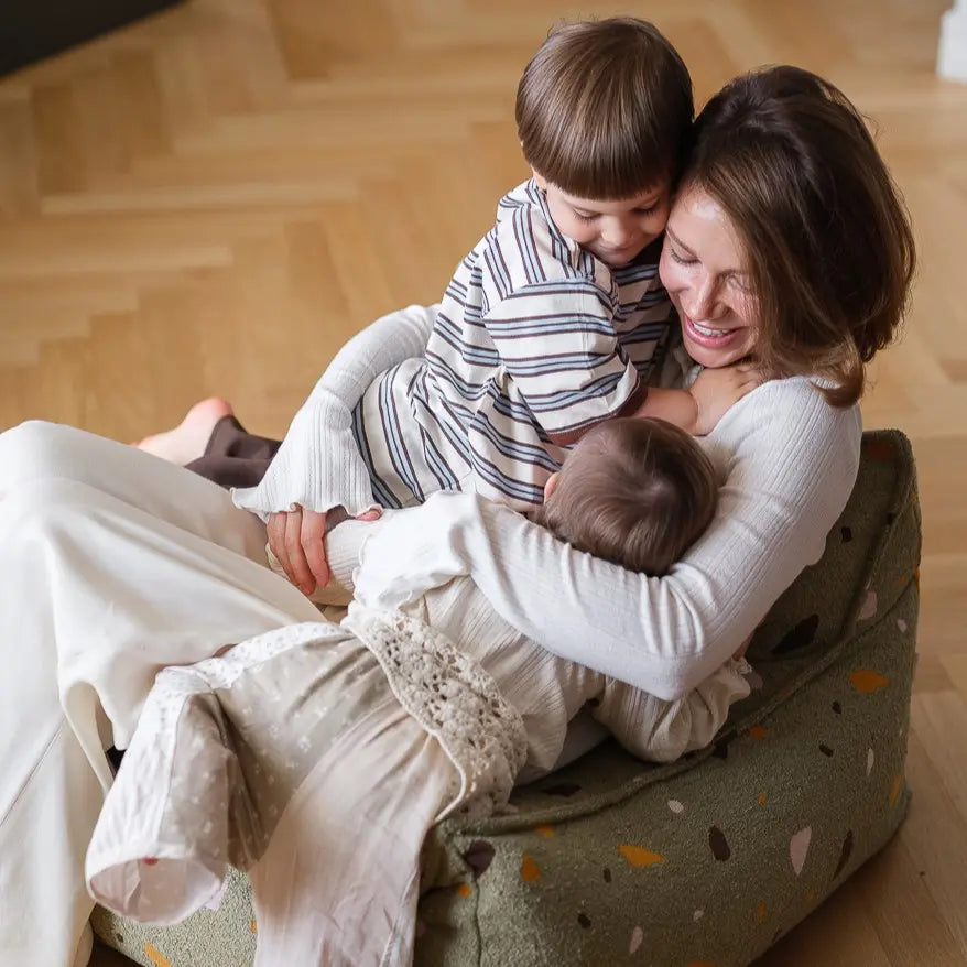 Fête des mères, une maman partageant un moment de tendresse sur un pouf en bouclette tout doux
